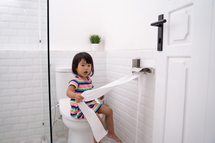 toddler pulling out toilet paper while playing around in the bathroom