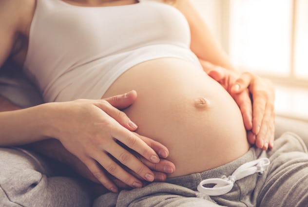 Cropped image of beautiful pregnant woman and her handsome husband touching belly