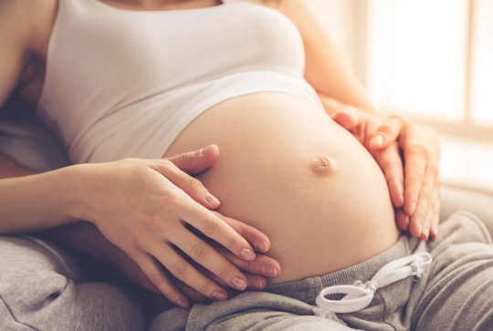 Cropped image of pregnant woman with partner's hands on belly