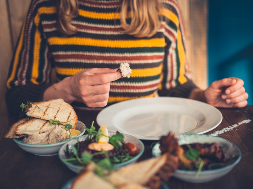 A young woman is eating tapas in a restaurant