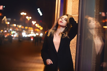 portrait of Beautiful young woman in black on a background of a night city