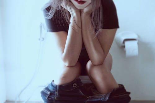 Woman sitting on toilet bowl thinking seriously - health problem concept