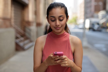 Young woman in city texting cell phone walking street