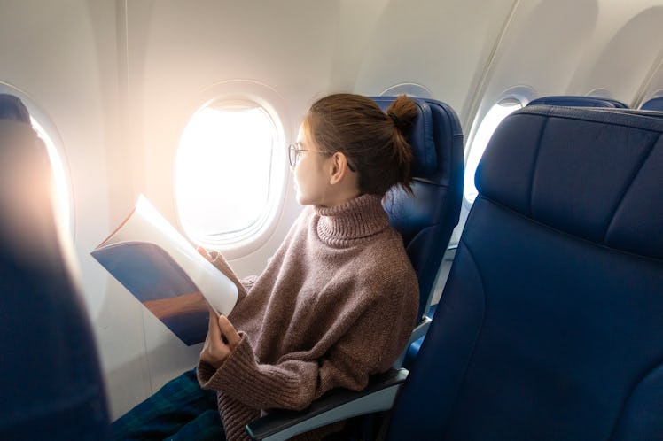 Beautiful Asian woman is reading magazine in airplane