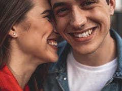 Close up of male and female smiling faces. Loving couple is standing with delight and embracing. Aff...