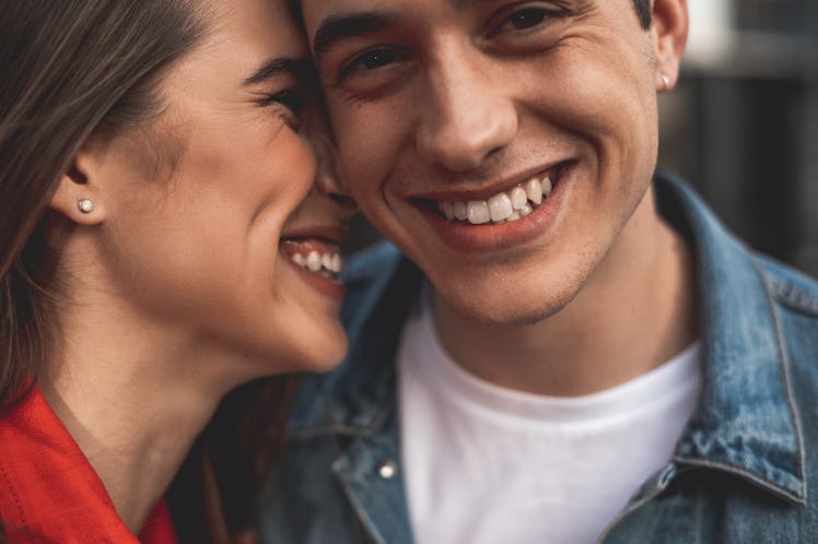 Close up of male and female smiling faces. Loving couple is standing with delight and embracing. Aff...
