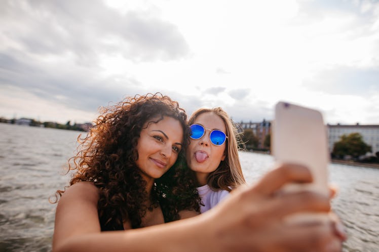 Two friends pose for a selfie by the beach.