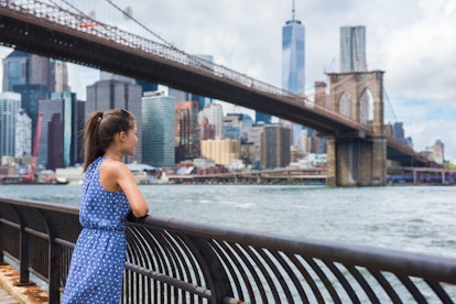 New York city urban woman enjoying view of Brooklyn bridge and NYC skyline living a happy lifestyle ...