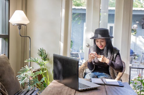 Charming beautiful tan skin Asian business chic woman hand work on laptop phone and write pen on not...