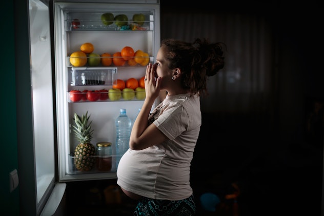 Pregnant woman at refrigerator choosing healthy food