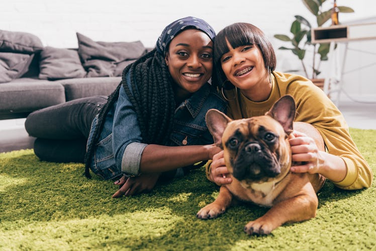 A woman and her dog are bonding with her partner while laying on a green rug. 