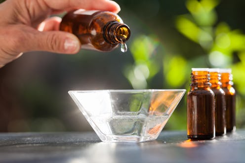 hand pouring essential oil in a bowl