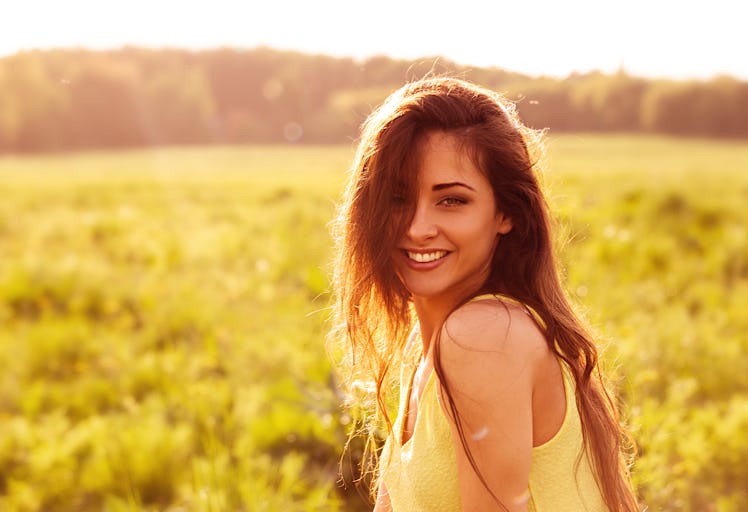 Beautiful toothy natural smiling relaxing woman looking happy with long amazing hair on nature brigh...