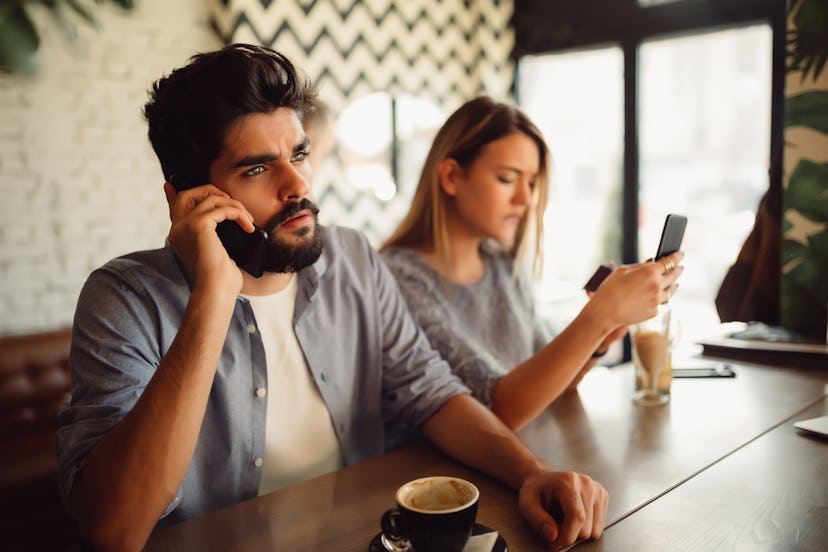 A beautiful young woman is upset to her handsome boyfriend because he is talking on the phone while ...