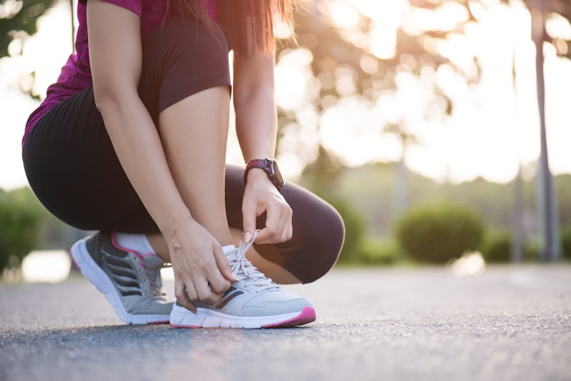 Running shoes - closeup of woman tying shoe laces. Female sport fitness runner getting ready for jogging in garden background.