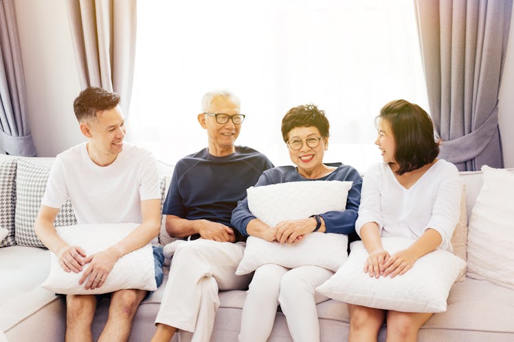 Asian family with adult children and senior parents relaxing on a sofa at home together