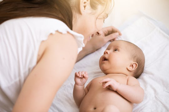 Young mother holding a newborn baby. Mom talks and laughs with her newborn son at home bedroom. Life...