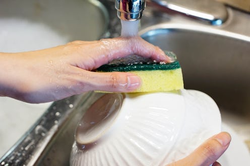 washing a white bowl with soapy suds in the kitchen sink