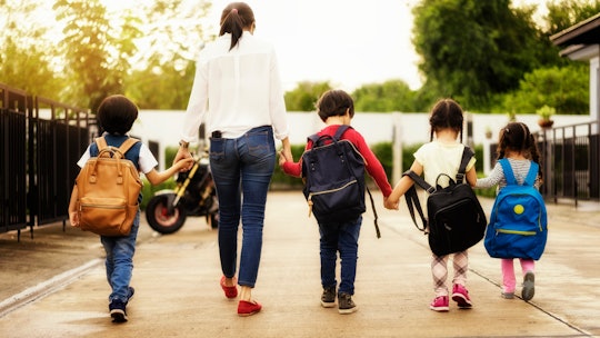 Mom and four kindergarten kids holding hand carry schoolbag walking to school bus.preschool concept....