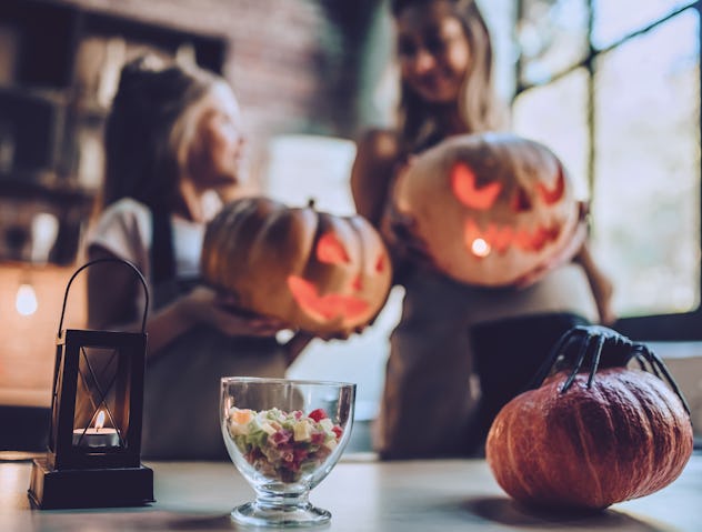 Happy Halloween! Attractive young pregnant woman with her little cute daughter are preparing to Hall...