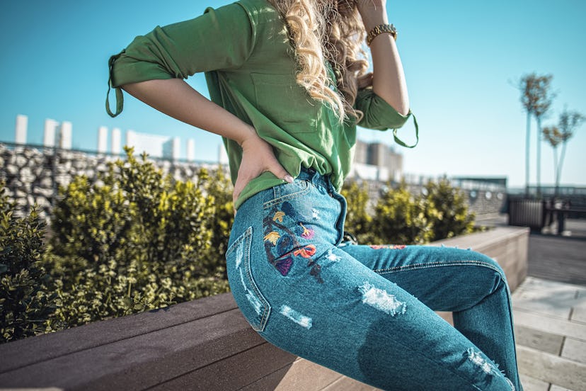 Outfit details of woman wearing jeans with embroidery 