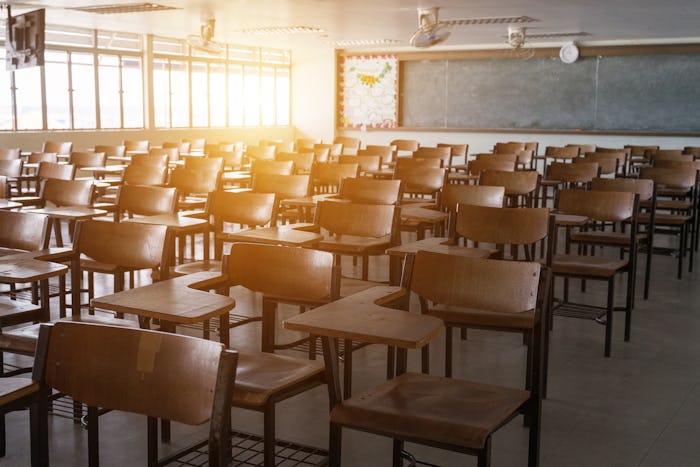 Empty school classroom with many wooden chairs. Wooden chairs in classroom. Wooden arranged in class...
