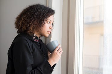 Alone and lonely young girl looking out the window as one of the most emotionally distant zodiac sig...