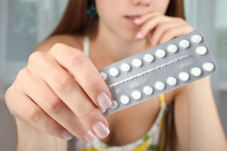Girl with contraceptive pills on the window background