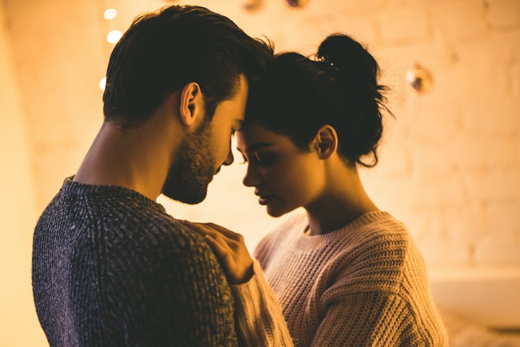 Passionate romantic couple in sweaters are spending time together before New Year at home. Tender co...