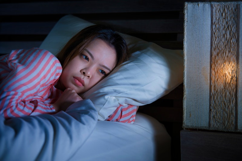young beautiful sad and depressed Asian Korean girl lying on bed late night awake looking thoughtful...