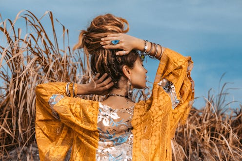 attractive young boho style woman in elegant dress posing at sunset