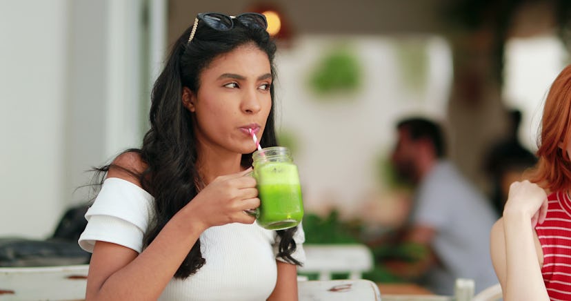Multiracial girl drinking healthy green juice outdoors