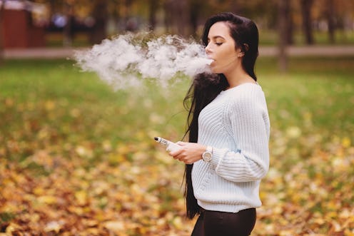 Woman vaping electronic hookah outdoor in autumn. Vape goodies