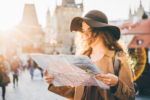 Girl with backpack looking at map, not being on her phone during vacation
