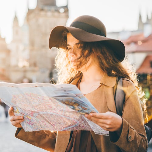 Girl with backpack looking at map, not being on her phone during vacation
