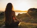 Woman meditating yoga alone at sunrise mountains. View from behind. Travel Lifestyle spiritual relax...