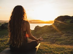 Woman meditating yoga alone at sunrise mountains. View from behind. Travel Lifestyle spiritual relax...