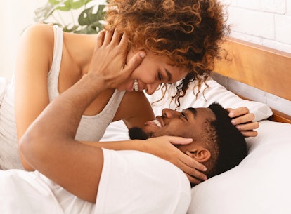 Good morning sex. Happy african-american man and woman kissing in bed, waking up in morning