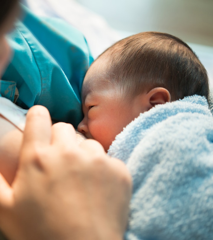 close-up of mom breastfeeding newborn with blue blanket, in an article answering the question, is it...