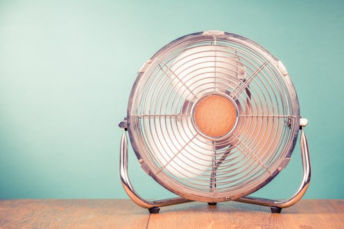 Retro portable office or home cooling fan in working mode standing on table. Vintage instagram style...