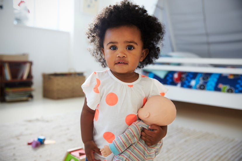 Portrait Of Baby Girl Playing With Doll In Playroom