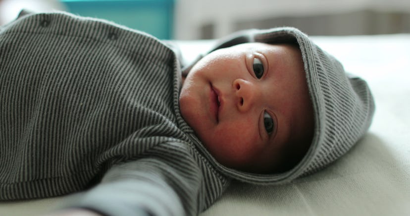 Adorable cute baby infant wearing hoodie clothing layed in bed