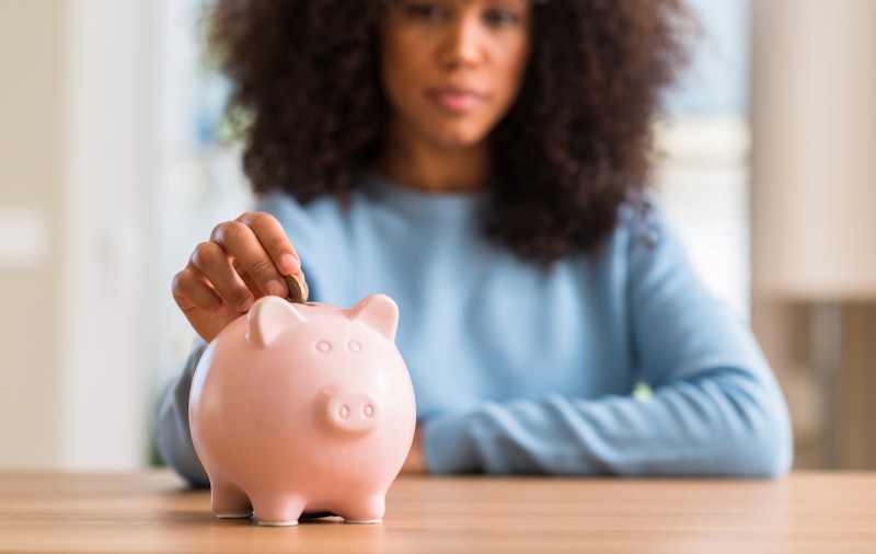 African american woman saves money in piggy bank with a confident expression on smart face thinking ...
