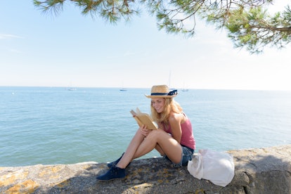 woman reading a book while relaxing outdoors