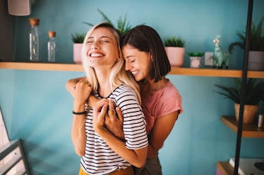 A lesbian couple embraces and smiles while spending the day together.