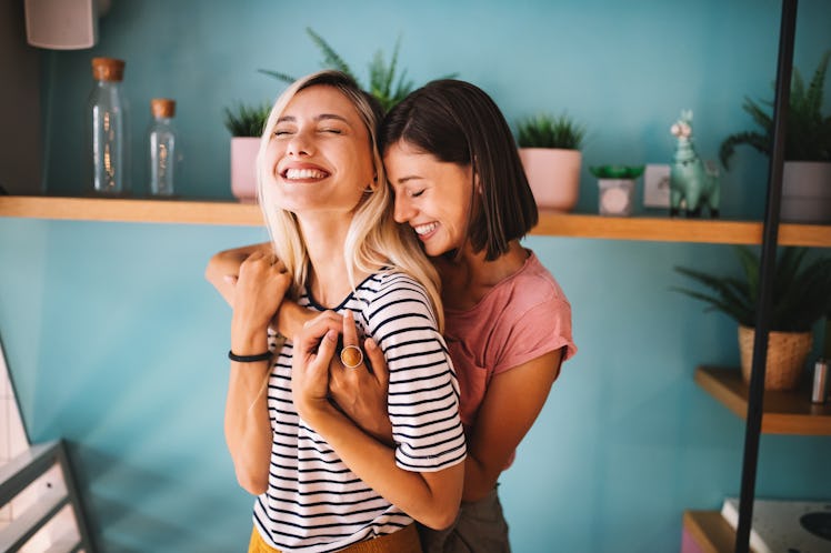 A lesbian couple embraces and smiles while spending the day together.
