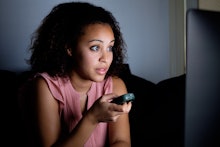 Young woman watching television at night