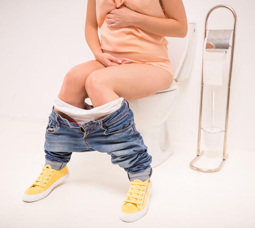 Young pregnant woman use the toilet, isolated on a white background