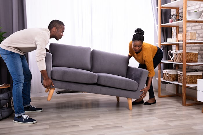 a young man and woman moving a sofa