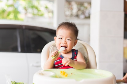 the baby learns to eat by himself. he can use spoon well. so he is very happy (focus at his face)